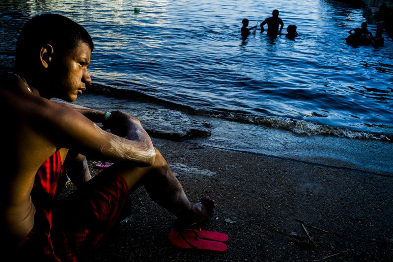 © Raphael Alves - A boy sits next to the Negro River to watch the sunset on May, 27th, 2016, in manaus, Amazonas, Brazil.
