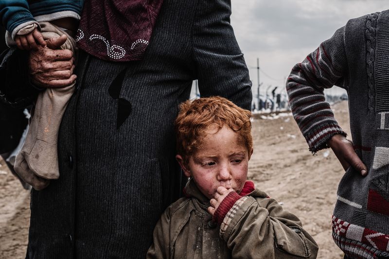 © Alexandra Howland - A mother of four stands outside the Medic Center inside Hamam Al Ali Refugee Camp. April 12, 2017 