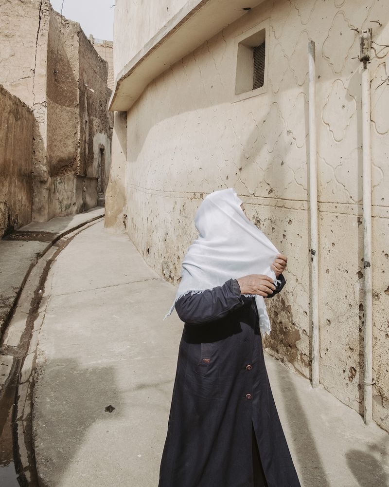 © Alexandra Howland - A woman fixes her head scarf in Old City West Mosul nearly a year following the proclaimed victory over the Islamic State.