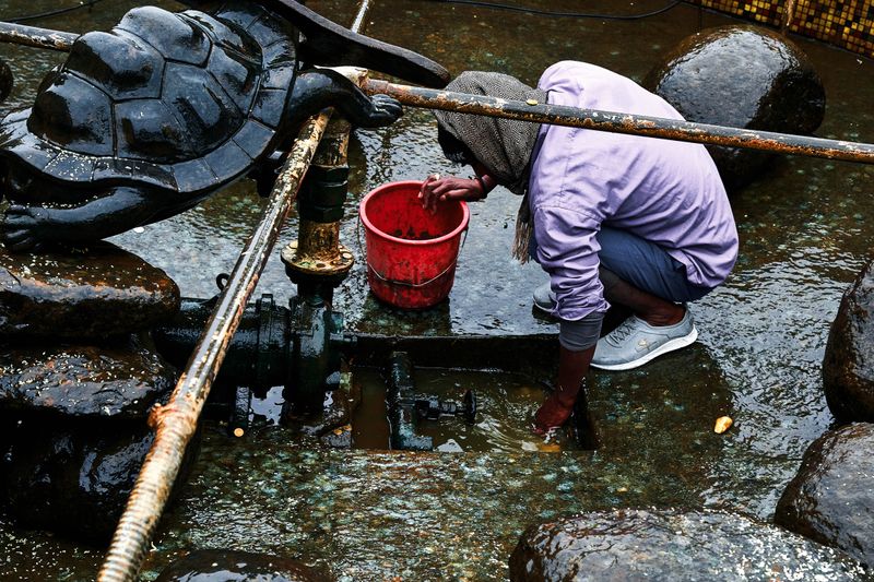 © tibhesh - A staff member gathers coins from a fountain in Japanese Stupa, which are thrown for good luck by pilgrims.