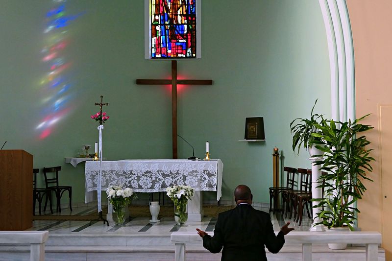 © Stefanos Chronis - African origin man is praying at the Catholic church of St Theresia. Athens Greece. Religion Catholic Christian