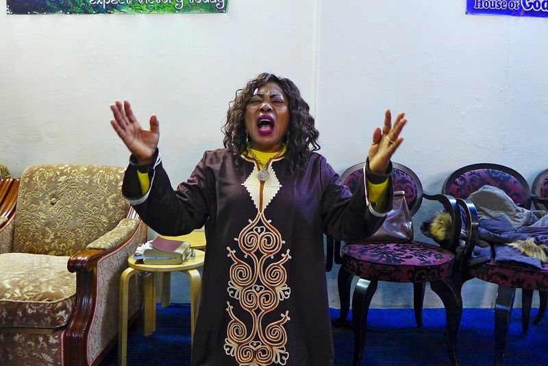 © Stefanos Chronis - Nigerian woman praying in immigrants place of worship in Athens. Religion Pentecostal Christian