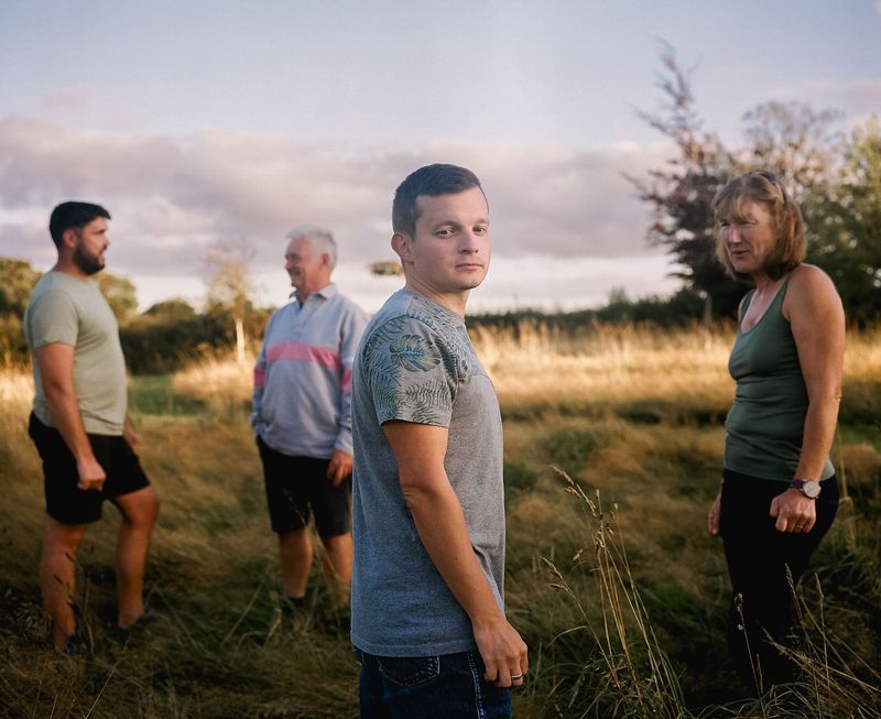 © Frankie Mills - Partners Dima (left) and Ihor (centre) and their sponsors photographed in their garden. September, 2023.