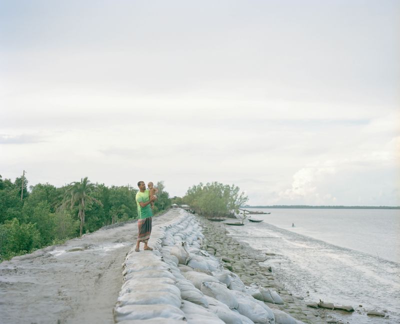 © Shunta Kimura - A man is looking after his baby by the Kholpetua River.