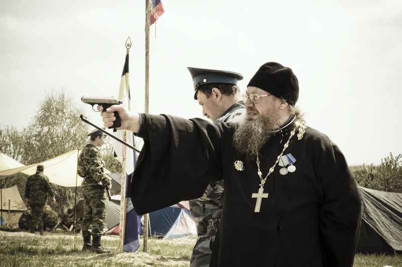 © Denis Tarasov - A priest of the Russian Orthodox Church firing a hand gun. Sverdlovsk region, Russia.