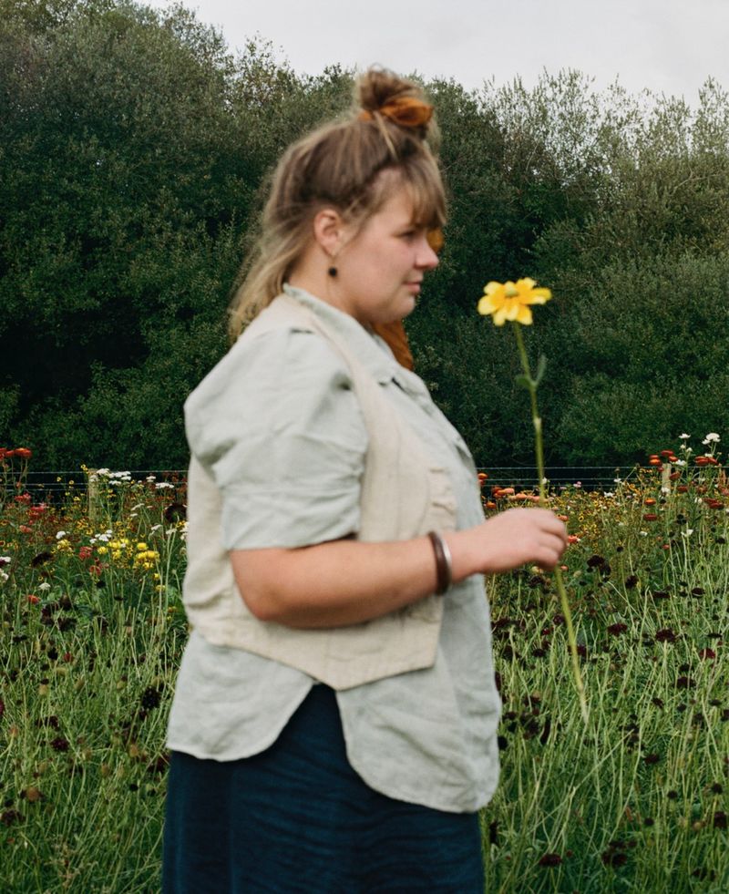© Hayleigh Longman - Ffion in front of huge bed of dye flowers growing on land. 2025