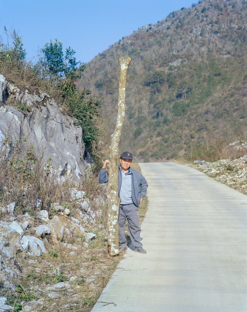 © Tianxi Wang - Person Carrying a Trunk Along a Mountain Path