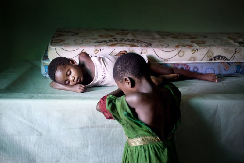 © Toby Binder - Two girls who are said to be bewitched sleeping on a covered billiard table in the children's home of CRARN.