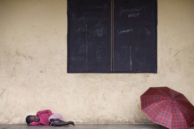 © Toby Binder - A boy sleeps while it’s raining, protected on the porch of the classrooms.