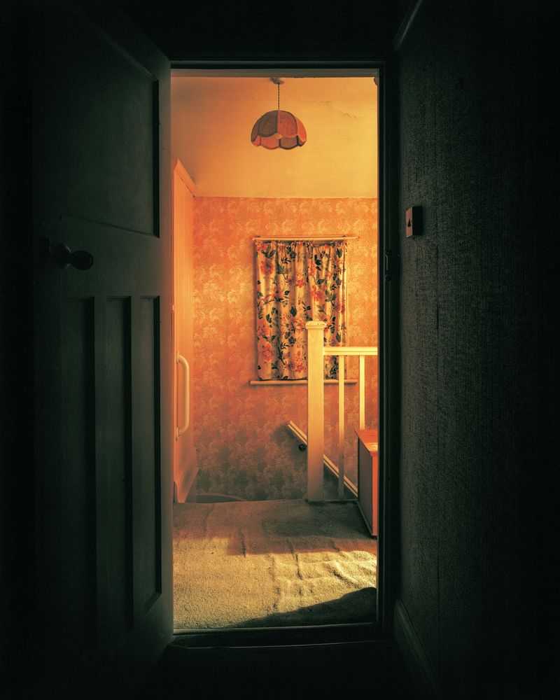 © Oliver Woods - A view of my childhood bedroom door opened and looking out onto the landing with the lights on, and taken at night.