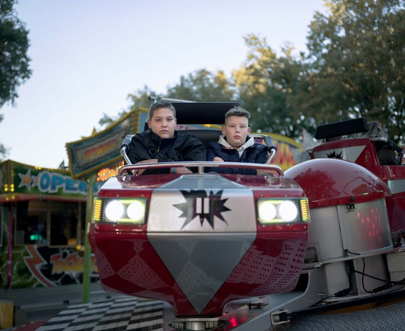 © Nina Schollaardt - Strangers Jarno (16) and Rico (11) at the Fun Fair in Zuid-Laren, Groningen, The Netherlands
