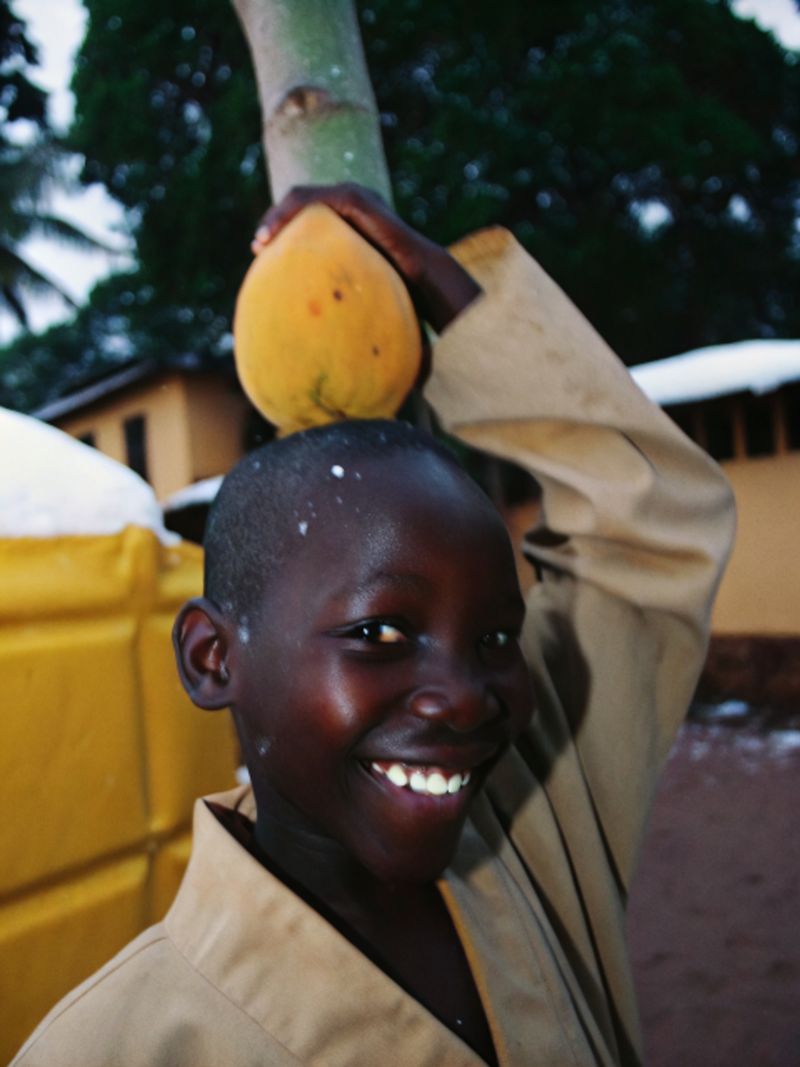 © yingying gao - August 2023, Dar es Salaam. A boy with fruit picked from a tree.
