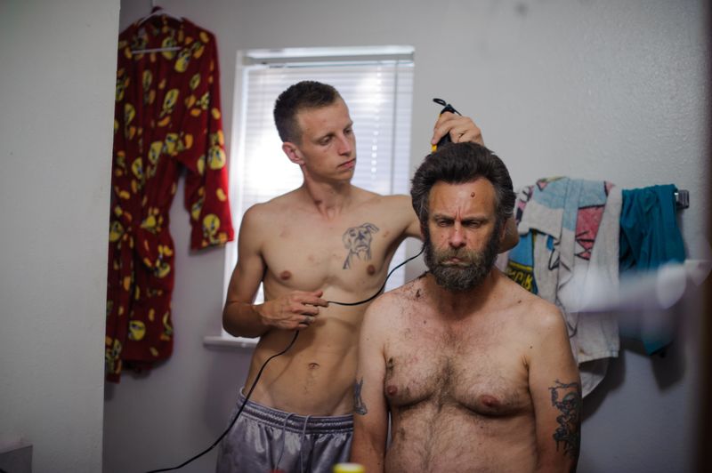 © Isadora Kosofsky - David shaves his father, Dave's, head before David's trial. At the trial, David was proven innocent on his charges.