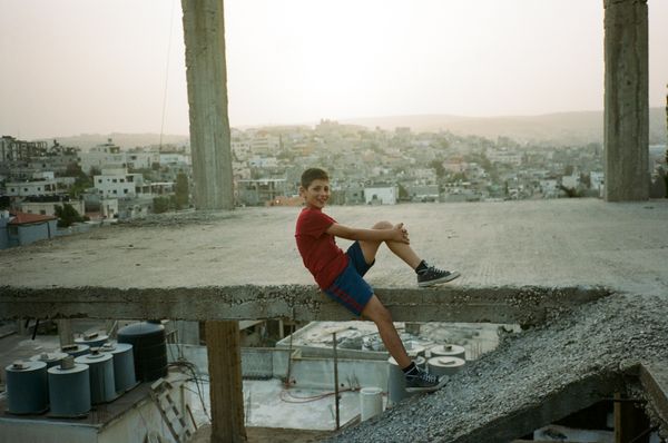© Melissa COLLETT - Yousef posing happily on one of the unfinished buildings in Dheisheh refugee camp