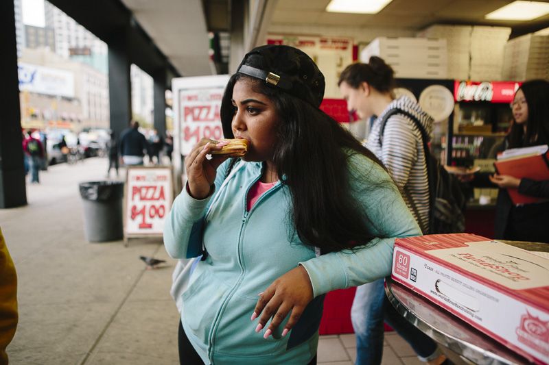 © Cassandra Giraldo - Anna Pimentel, 16, enjoys a slice of pizza after school on Flatbush Avenue in Brooklyn, New York October 27, 2015.