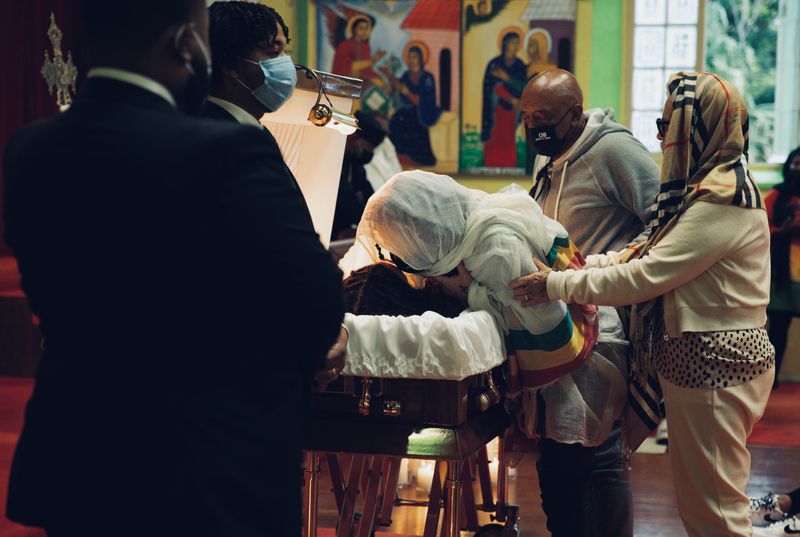 © Jayde Gibbons - The mother of Osagi Bascome being supported by her sister and father at the casket of her youngest child.