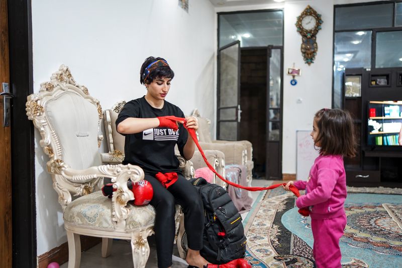© Ali Rad - Hanieh is preparing for her boxing practice at home while her daughter watches her.