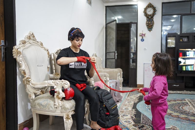© Ali Rad - Hanieh is preparing for her boxing practice at home while her daughter watches her.