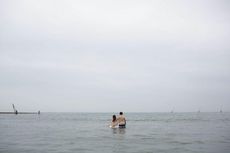 © Taro Karibe - Senji Nakajima stares at the horizon with his Love Doll 'Saori' at Zaimokuza beach on July 8, 2016 in Kanagawa, Japan.