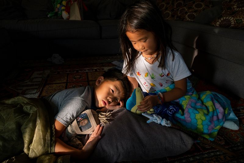 © Arin Yoon - Teo holds a doll that has a photo of John inserted in a sleeve, while Mila takes care of her stuffed animal.