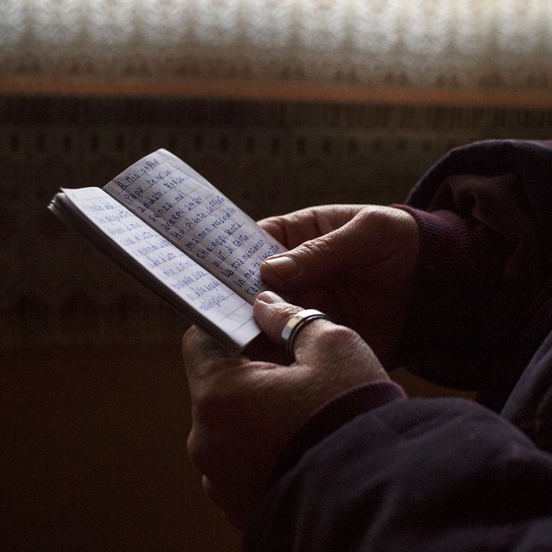 © Melissa Ianniello - Pina Capizzo holding a notebook which contains a poem she wrote and dedicated to her father (Assemini – Sardinia).