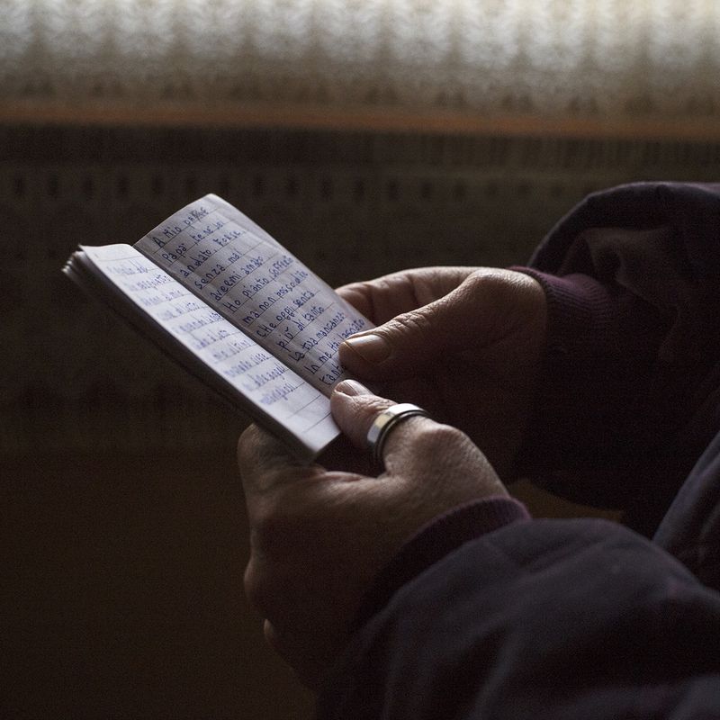 © Melissa Ianniello - Pina Capizzo holding a notebook which contains a poem she wrote and dedicated to her father (Assemini – Sardinia).