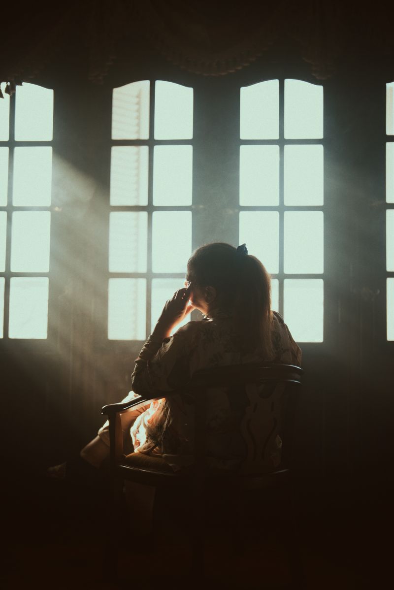 © Nayra Aly - My mother Laila sitting by the window in her usual spot in the darkness of her bedroom.