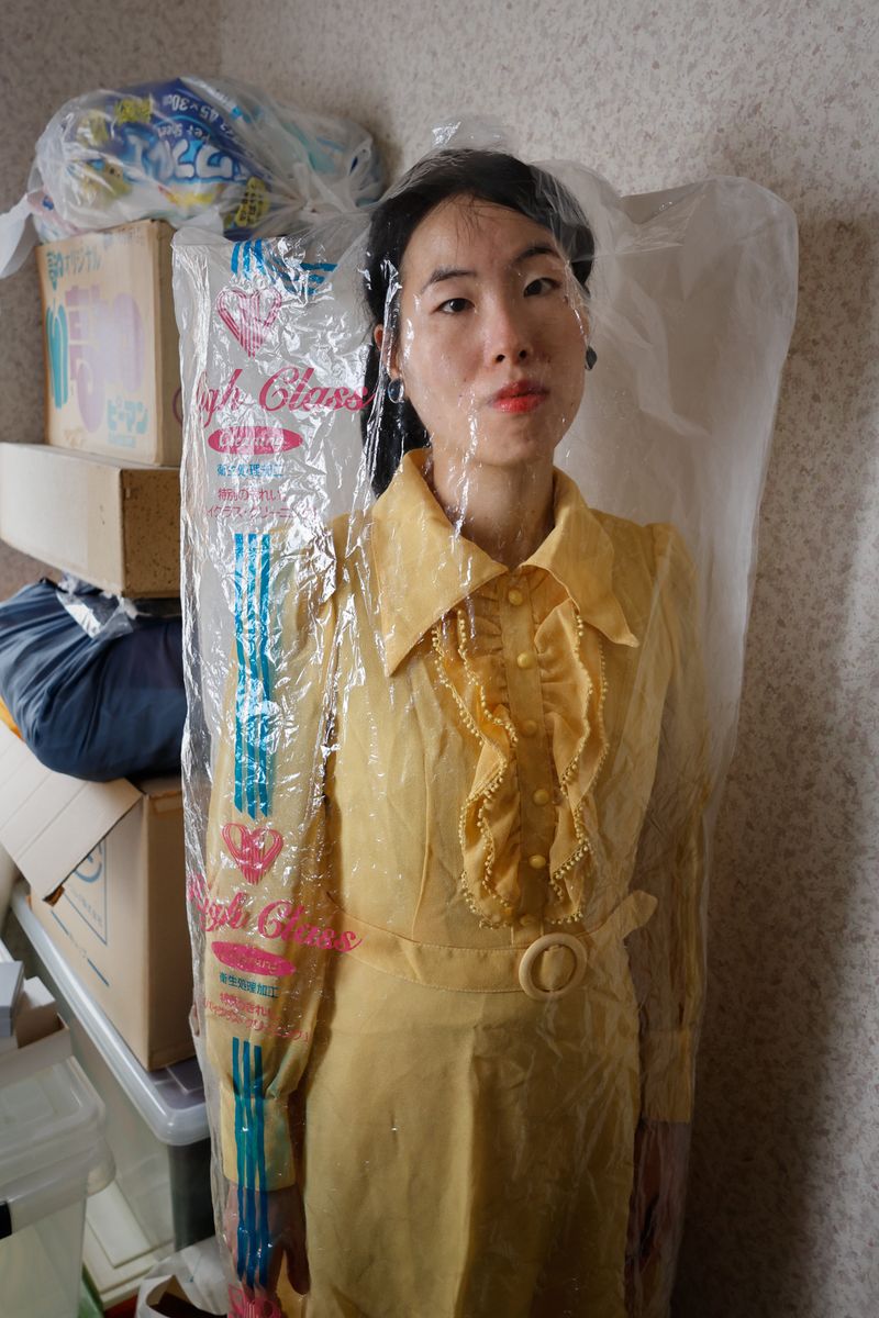 © Yuki Furusawa - Me wearing my grandmother’s dress, unworn for about 40 years, still covered by its dry cleaner's plastic.