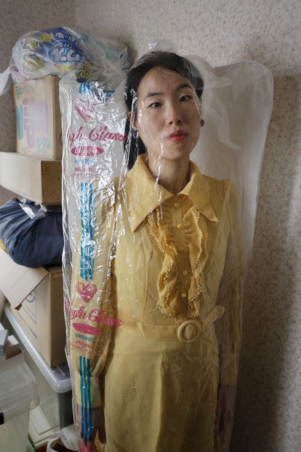 © Yuki Furusawa - Me wearing my grandmother’s dress, unworn for about 40 years, still covered by its dry cleaner's plastic.