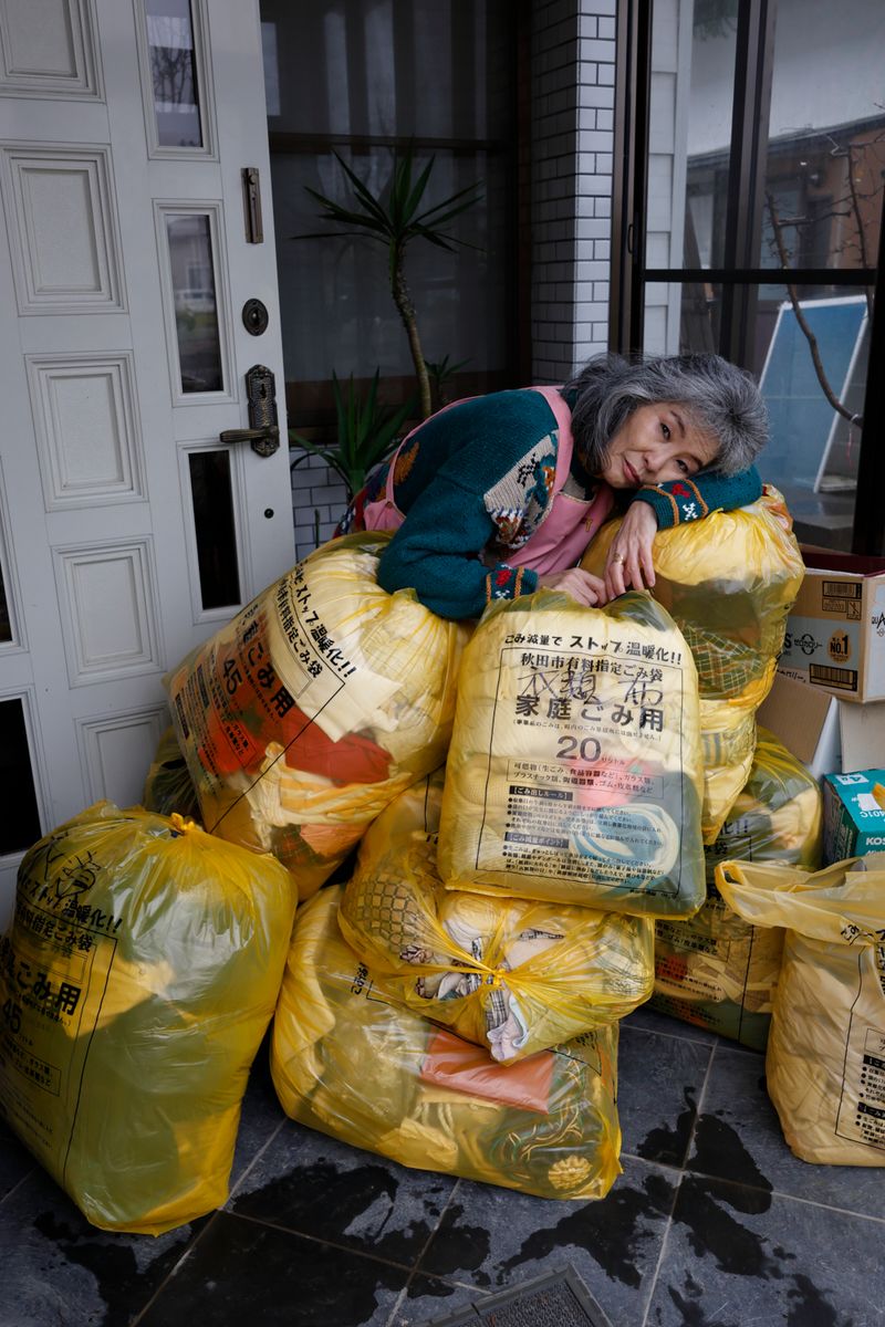 © Yuki Furusawa - My mother surrounded by trash bags filled with abandoned old clothes.