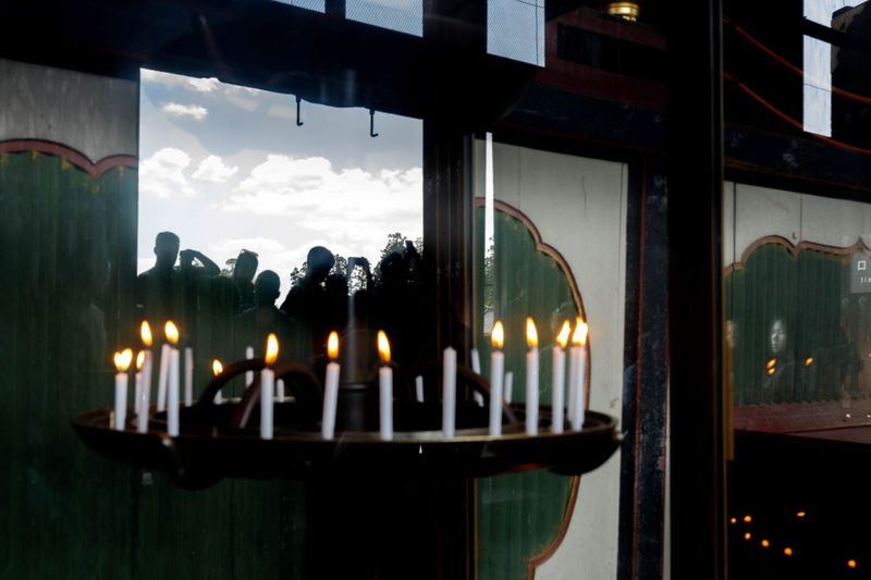 © ROBERTA LODI - "Candles and Reflections" Rows of lit candles reflecting figures, merging presence and absence.