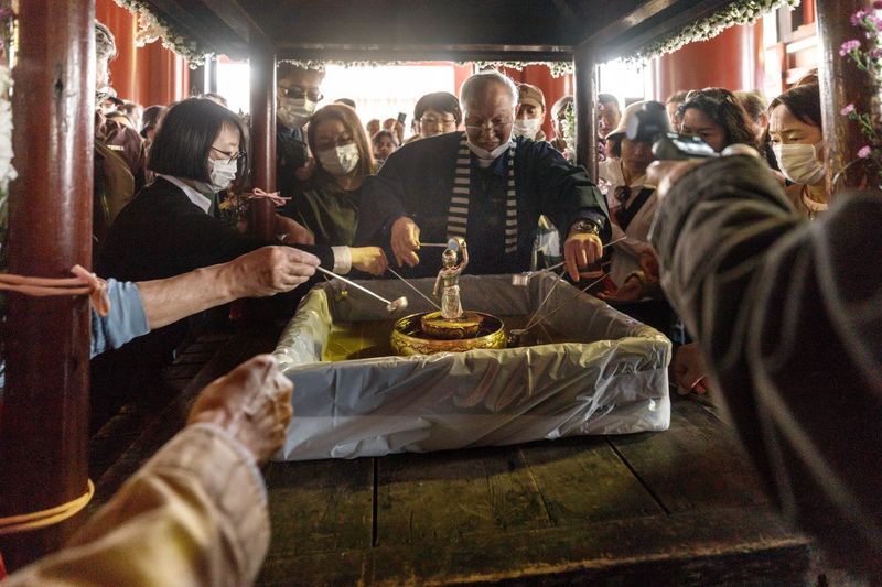 © ROBERTA LODI - "Buddha’s birthday ritual"   Hands pouring water over the statue of baby Buddha during a traditional celebration.