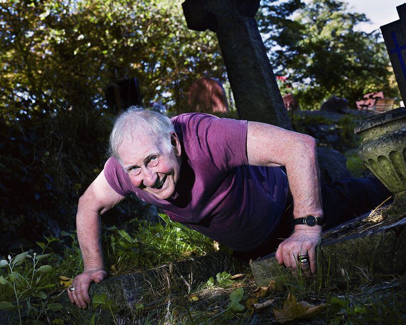 © Piotr Karpinski. Man Exercising Between Graves 