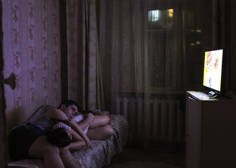 © Alexey Vasilyev - A young couple Ivan and Inna are watching TV at home.