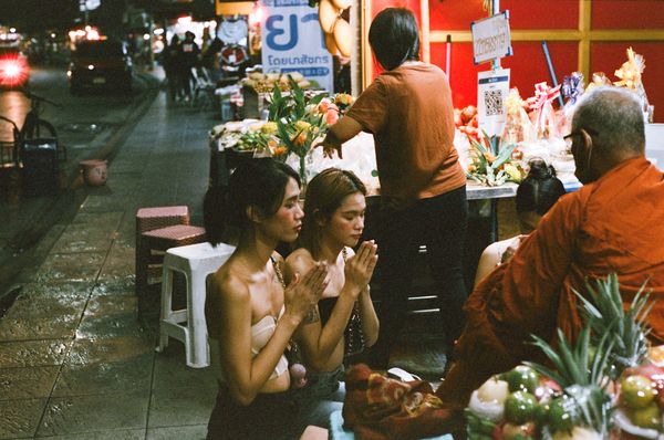 © Elizabeth Waterman - Ladyboys Nat and friends give alms to a monk in the early morning hours, after getting off work in the gogo bar.