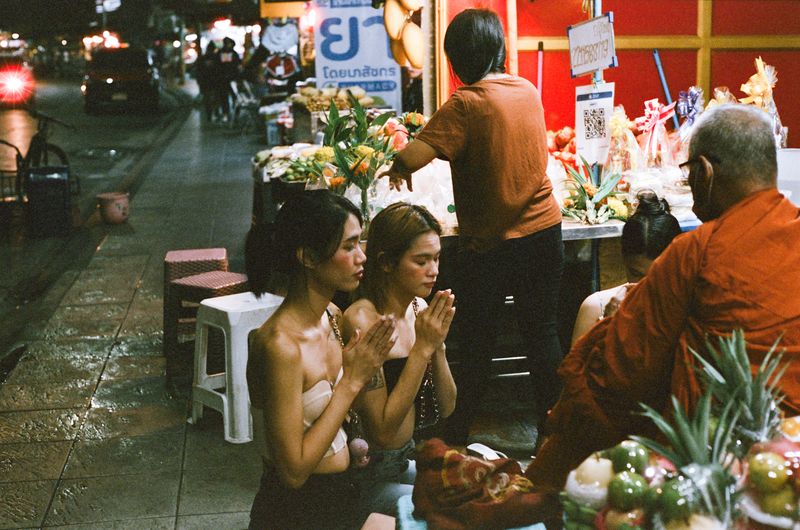 © Elizabeth Waterman - Ladyboys Nat and friends give alms to a monk in the early morning hours, after getting off work in the gogo bar.