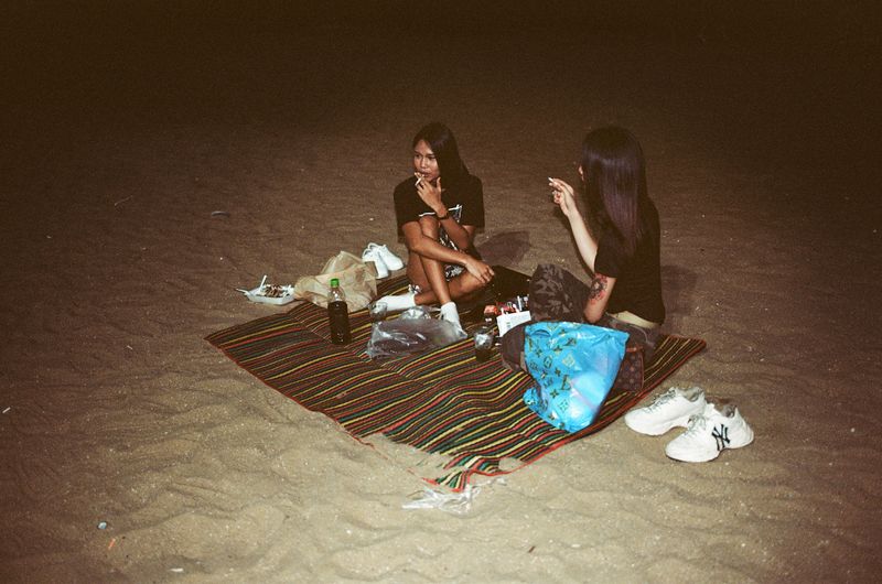 © Elizabeth Waterman - Two young Ladyboys relax on the beach after work in the early morning hours, in Pattaya City, Thailand
