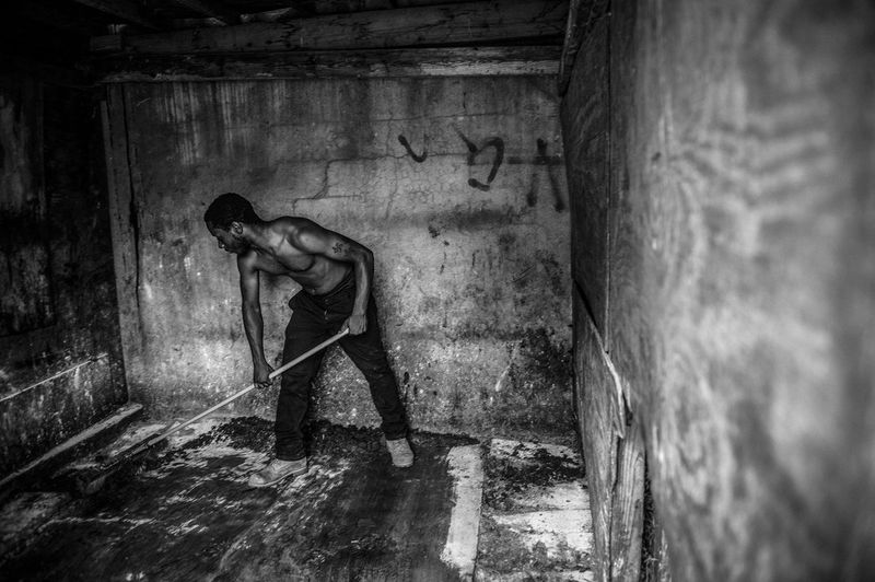 © Charles Mostoller - Dominique Waugh, 18, sweeps away manure and barn lime in one of the stalls.