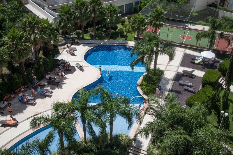 © Chiara Ferronato - A swimming pool and a tennis courtyard as seen from an apartment within a gated community on a Sunday afternoon.