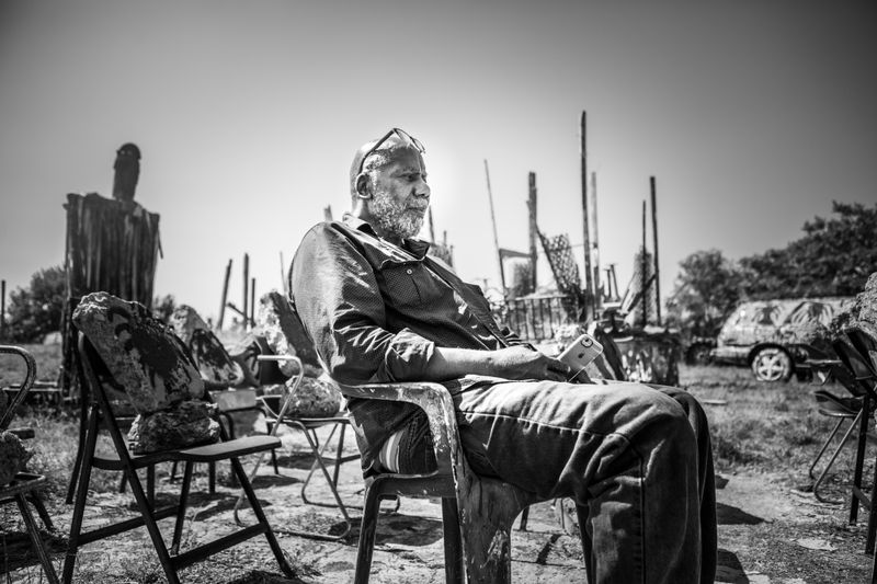 © JANICE MILHEM - Dabls contemplates his art installation arrangement which faces a major highway leading to the city.