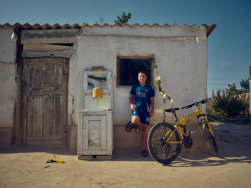 © Louise Amelie - Something Yellow. A young boy with his bicycle in the courtyard of a private home in Tong.