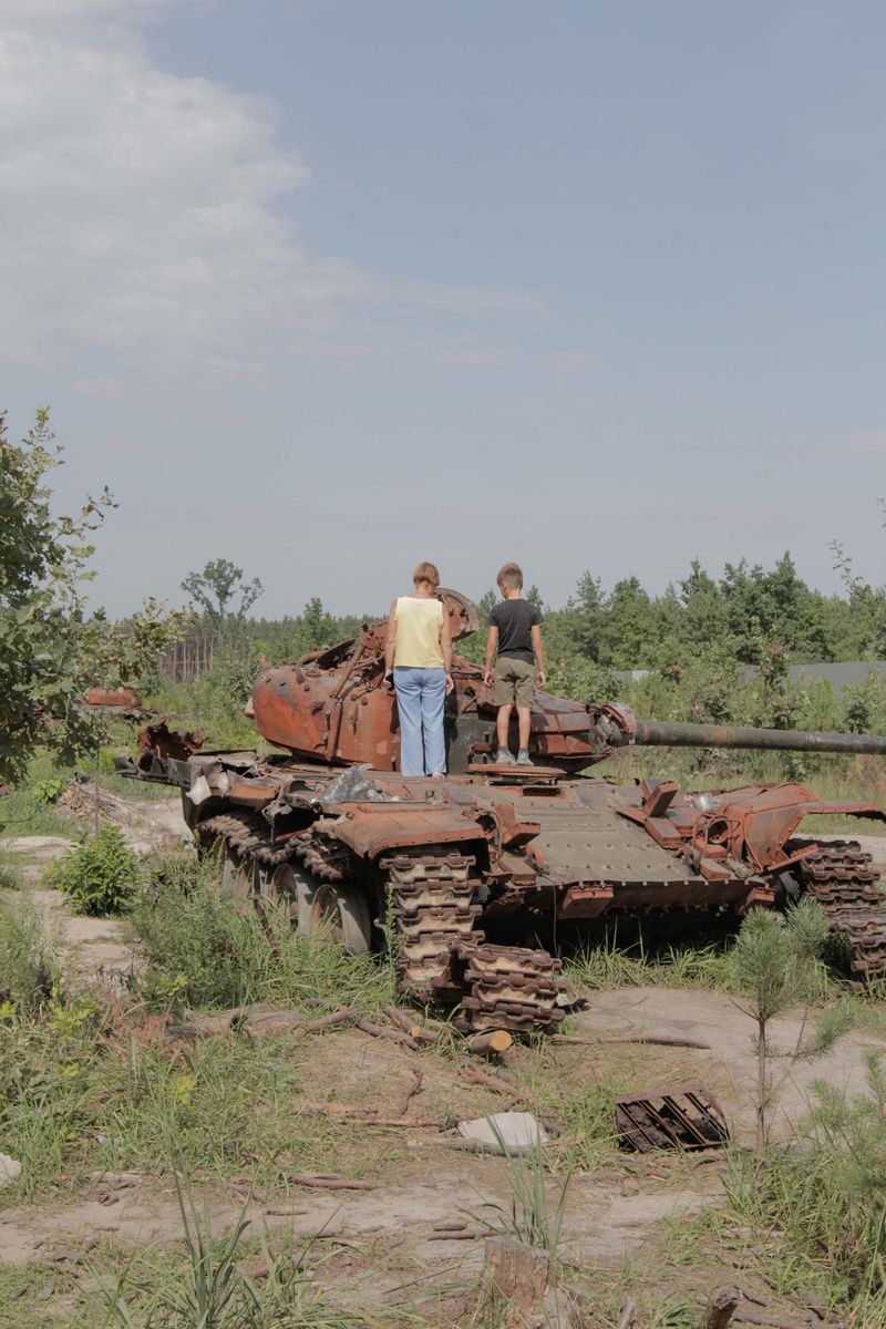© Nazar Furyk - 7. A woman and a child examine a burnt Russian tank. Dmytrivka. August, 2022.
