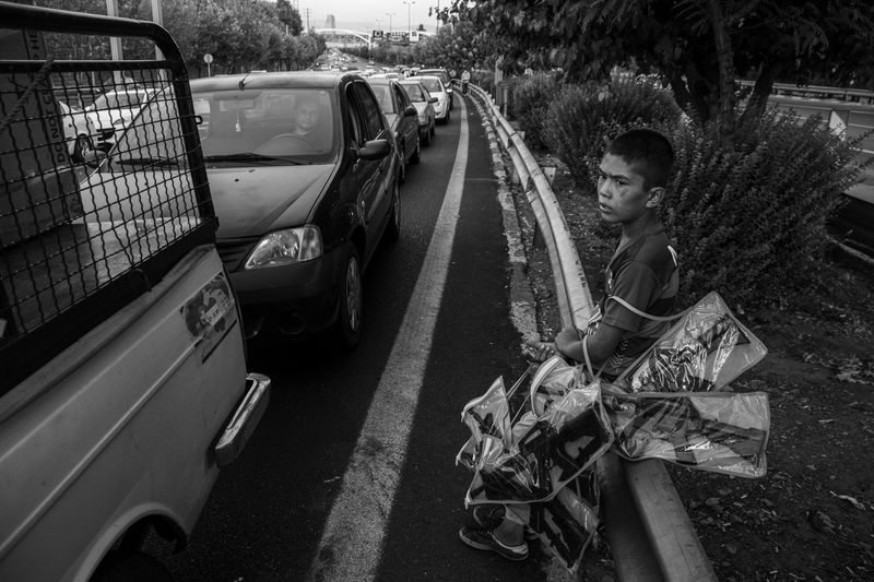 © Zobair Movahhed - An Afghan refugee child sells toy assault rifles on the side of a highway in Tehran.