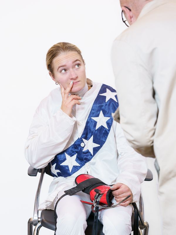 © Theresa Wißmann - A jockey is being weighed on the weighing chair before the race. One of the judges walks over and addresses the jockey.