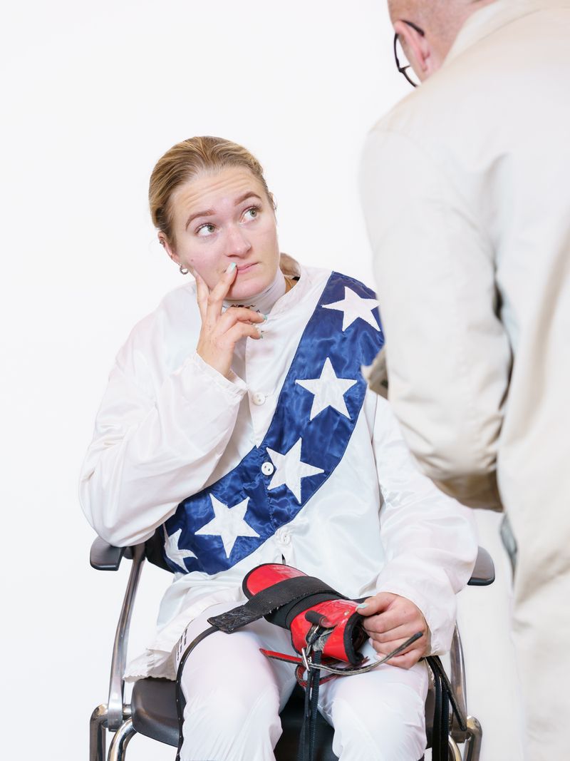 © Theresa Wißmann - A jockey is being weighed on the weighing chair before the race. One of the judges walks over and addresses the jockey.