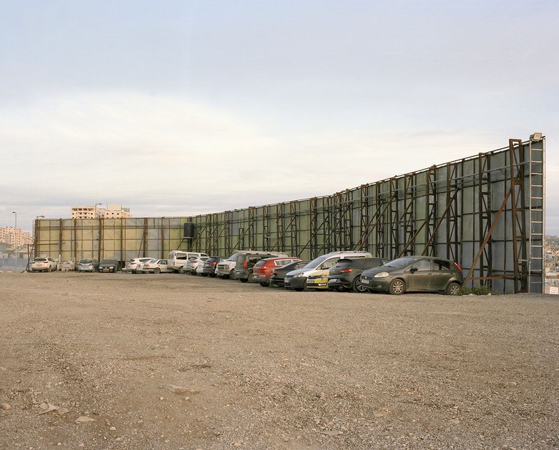 © Saja Quttaineh - Car parking behind the billboards in Al-Ram town, 2021