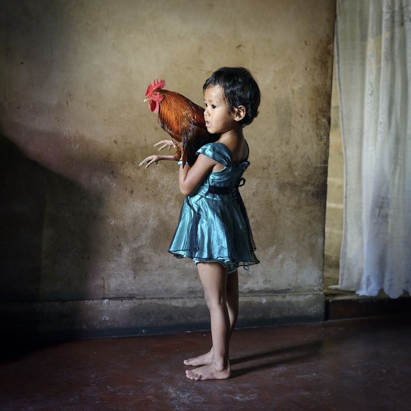 © Karolin Klüppel - Yasmin holds a rooster. She loves to catch and play with it after dawn.