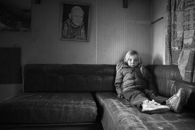 © Rebecca Moseman - A young traveler girl sits alone in her family's empty caravan by the roadside.