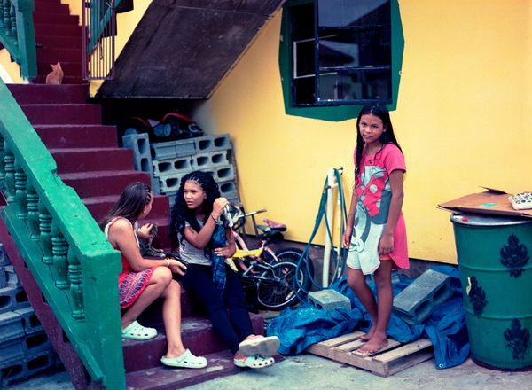 © Kelly-Ann Bobb - Sofia stands with her friends in the yard of the house rented by her family.