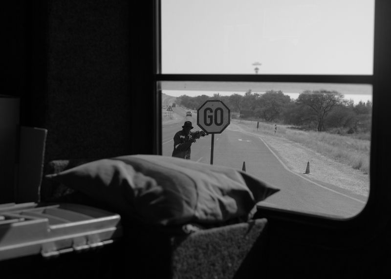 © Reuben - (On We Go) Taken a few days into hitchhiking with with a group of tourists, a man holds a stop sign.
